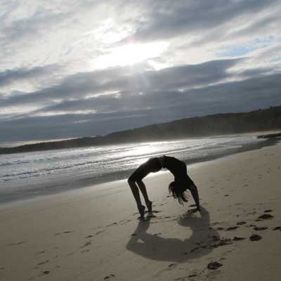 Dru yoga - chakrasana posture at the beach