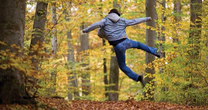Man jumping for joy in forest path