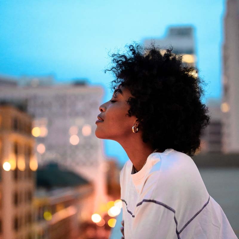 woman-meditating-colourful-city-background